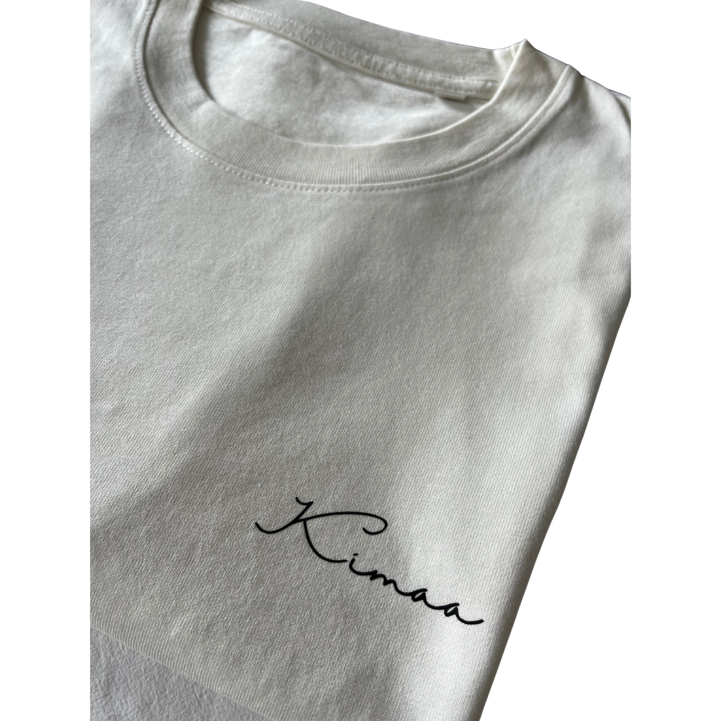 Kimaa chest logo on beige Bankoo tee — subtle branding on eco-friendly organic cotton.