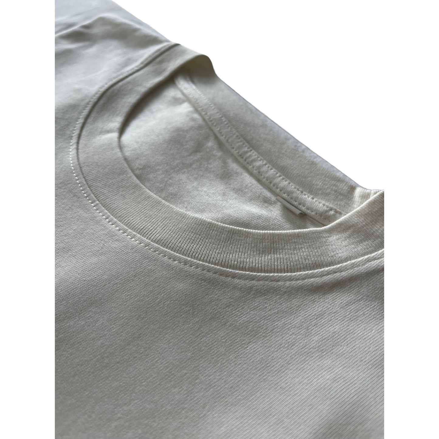 Closeup of neckline stitching on Kimaa’s Bankoo beige organic cotton T-shirt — ethical and durable.