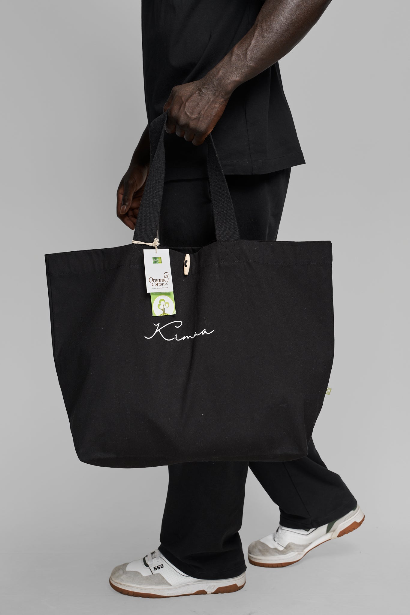 Black Maabo organic cotton tote bag carried on the side showing natural texture and minimalist design