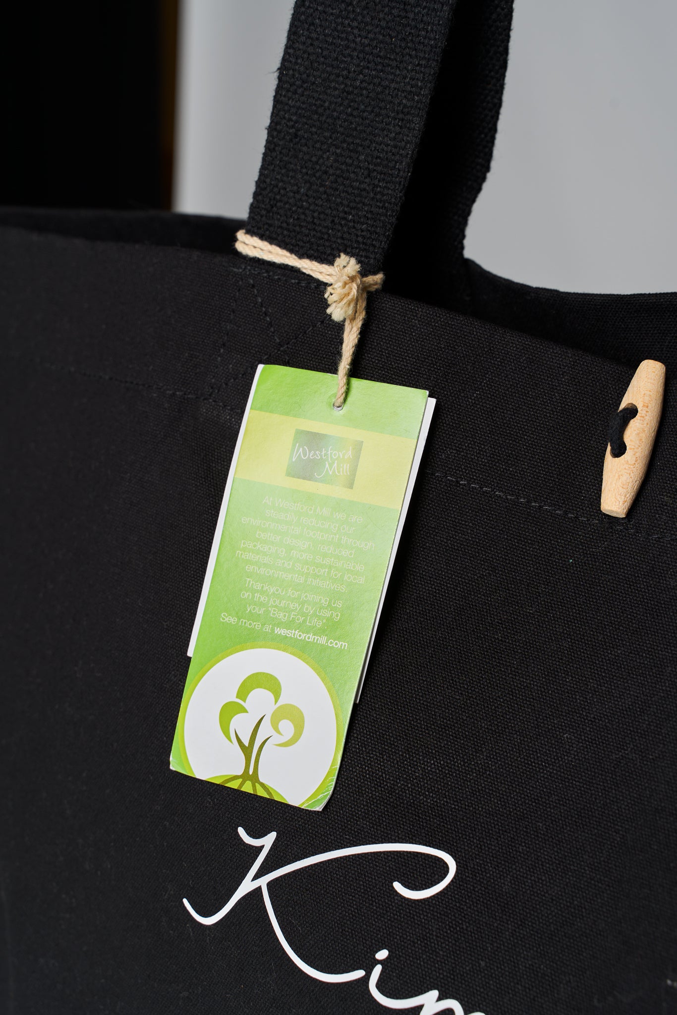 Closeup of organic cotton label hanging from Maabo black tote bag handle