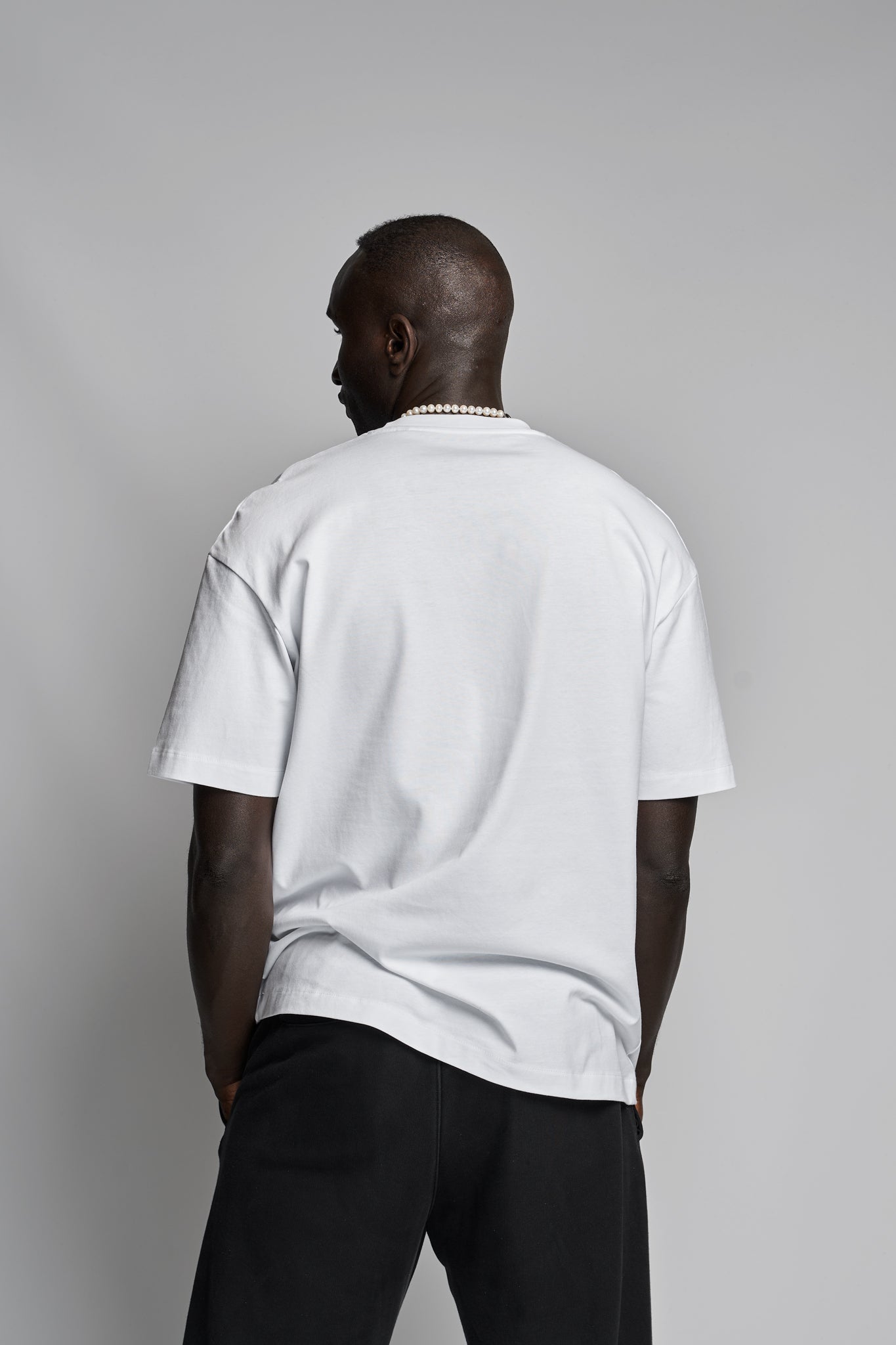 Back view of model wearing Kimaa’s Senumaa T-shirt — minimalist streetwear in white organic cotton.