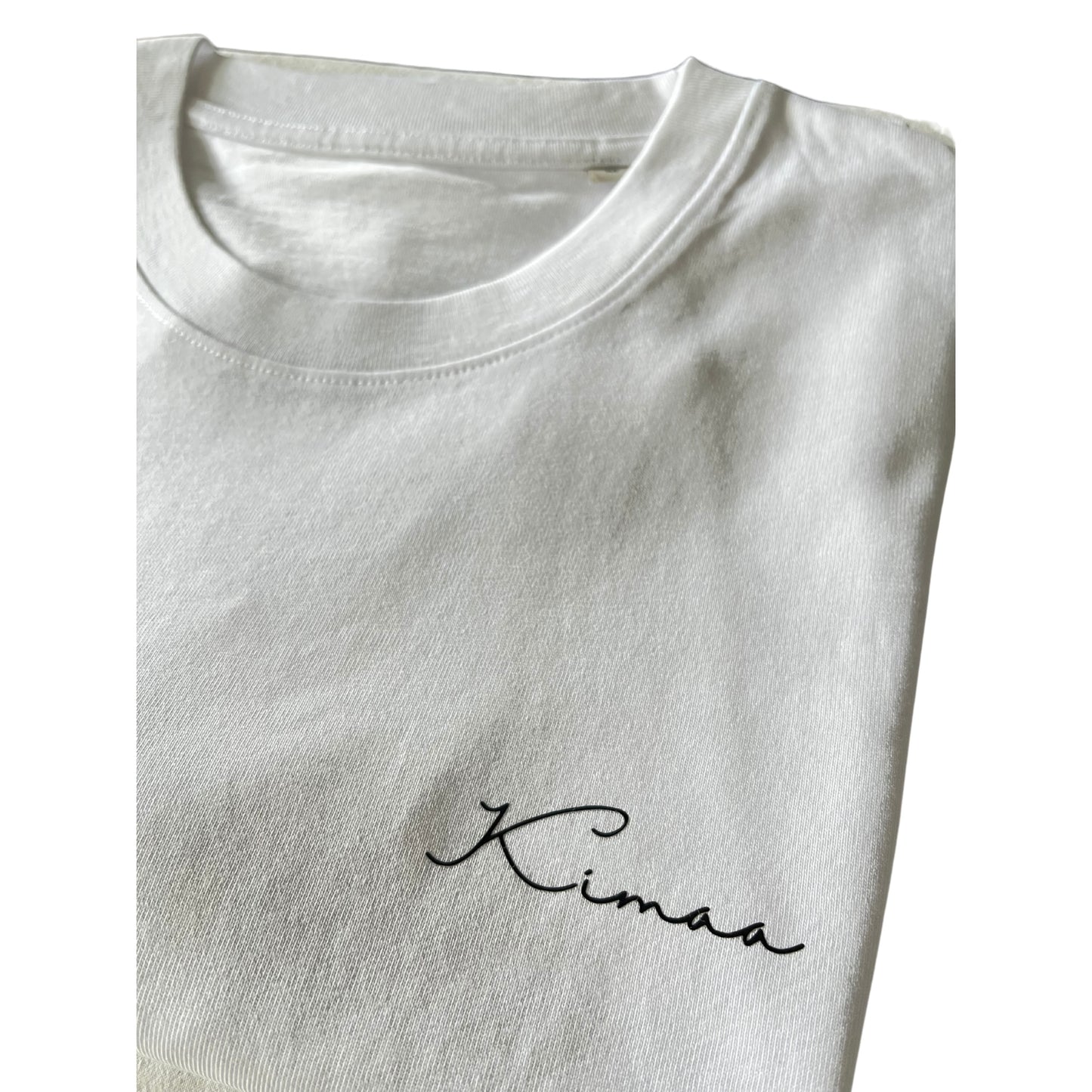 Kimaa logo closeup on chest of Senumaa white T-shirt — sustainable, subtle branding.