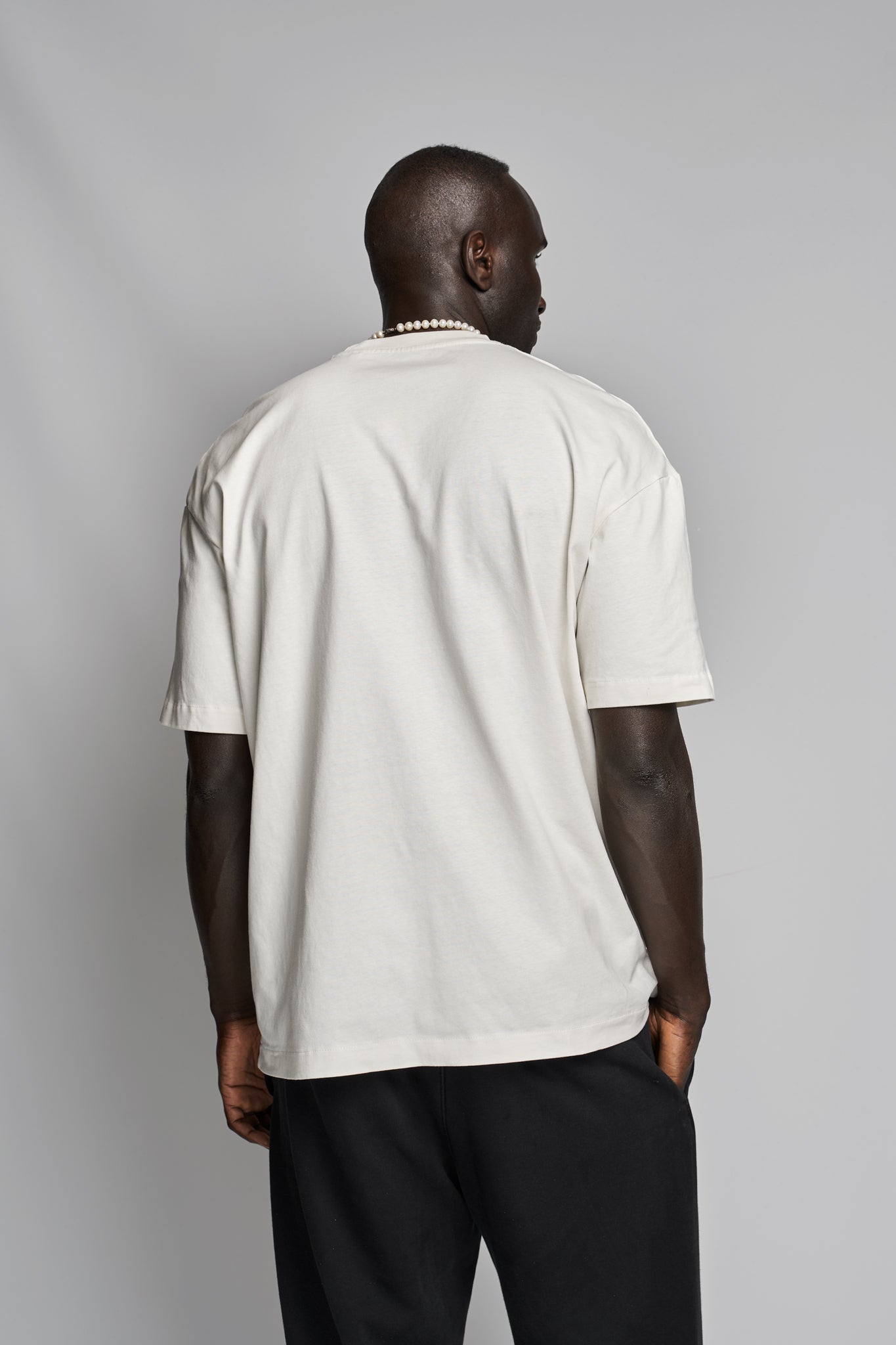 Back view of Bankoo beige T-shirt worn by model — dropped shoulder, relaxed fit by Kimaa.