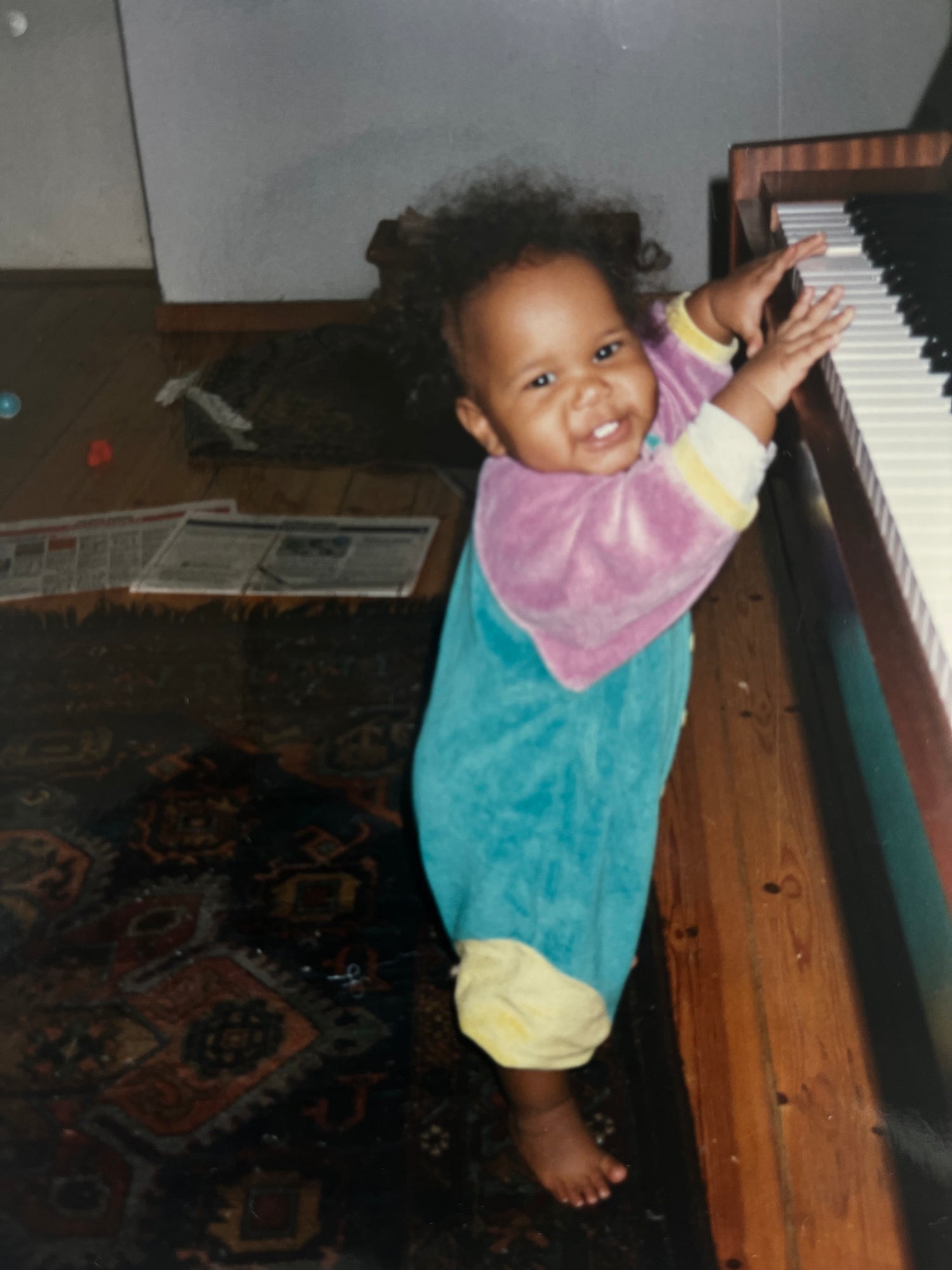 Vintage baby photo of Kimaa founder playing piano, symbolising roots, creativity, and Afro-Nordic cultural identity