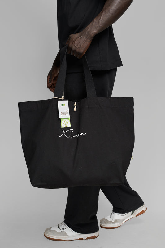 Black Maabo organic cotton tote bag carried on the side showing natural texture and minimalist design