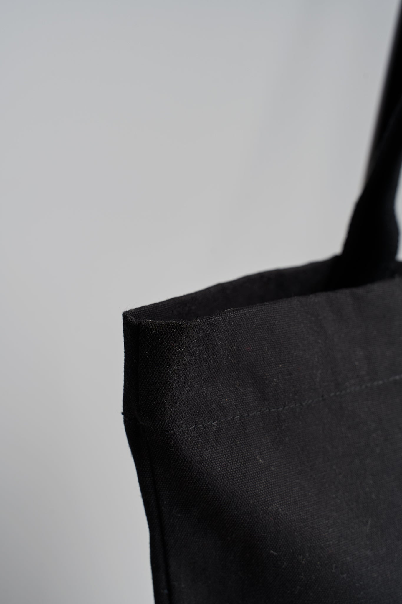 Closeup of reinforced stitching along edge of Maabo black organic cotton tote bag
