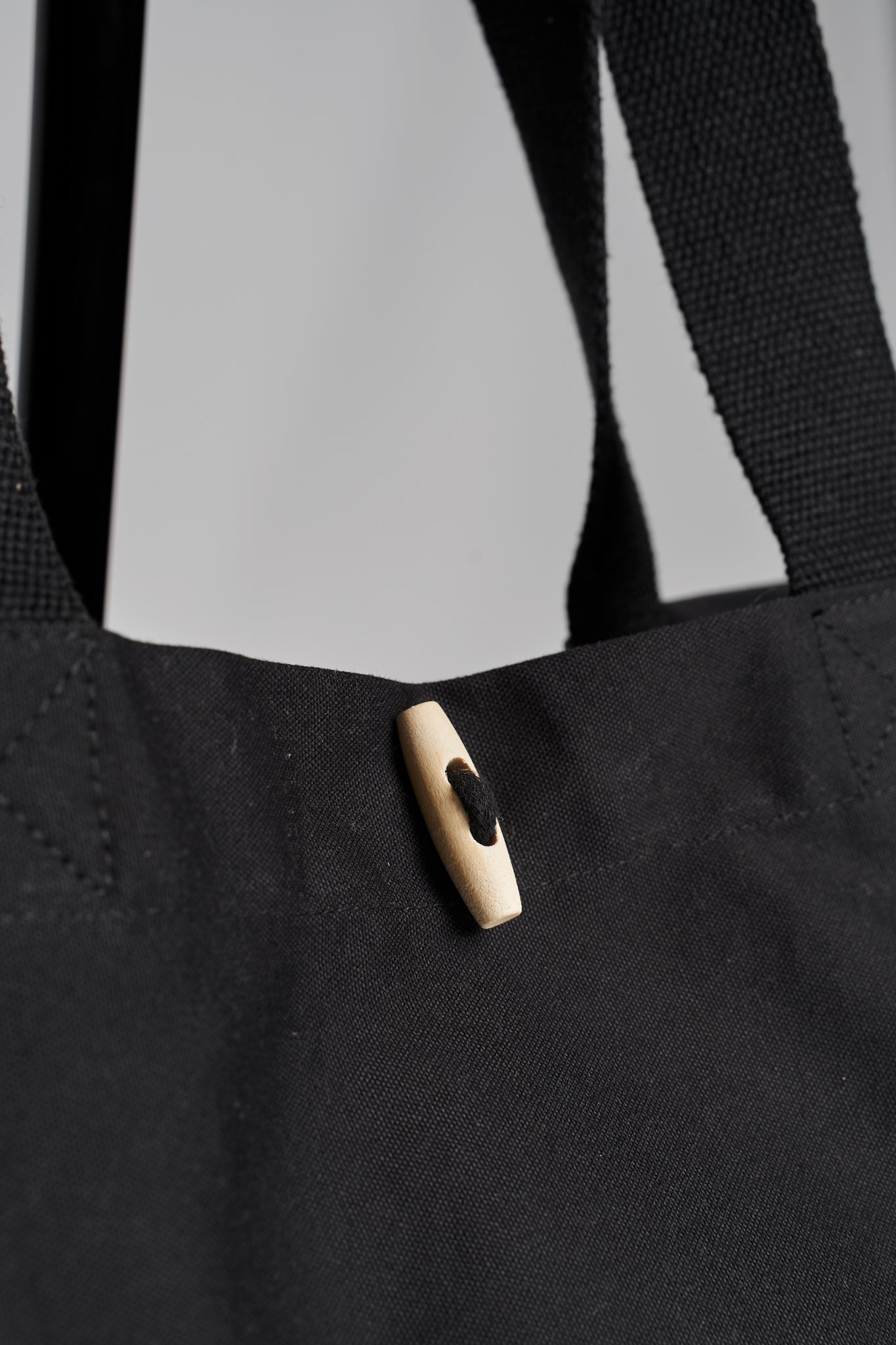 Detailed closeup of wooden toggle closure on black Maabo organic cotton tote bag