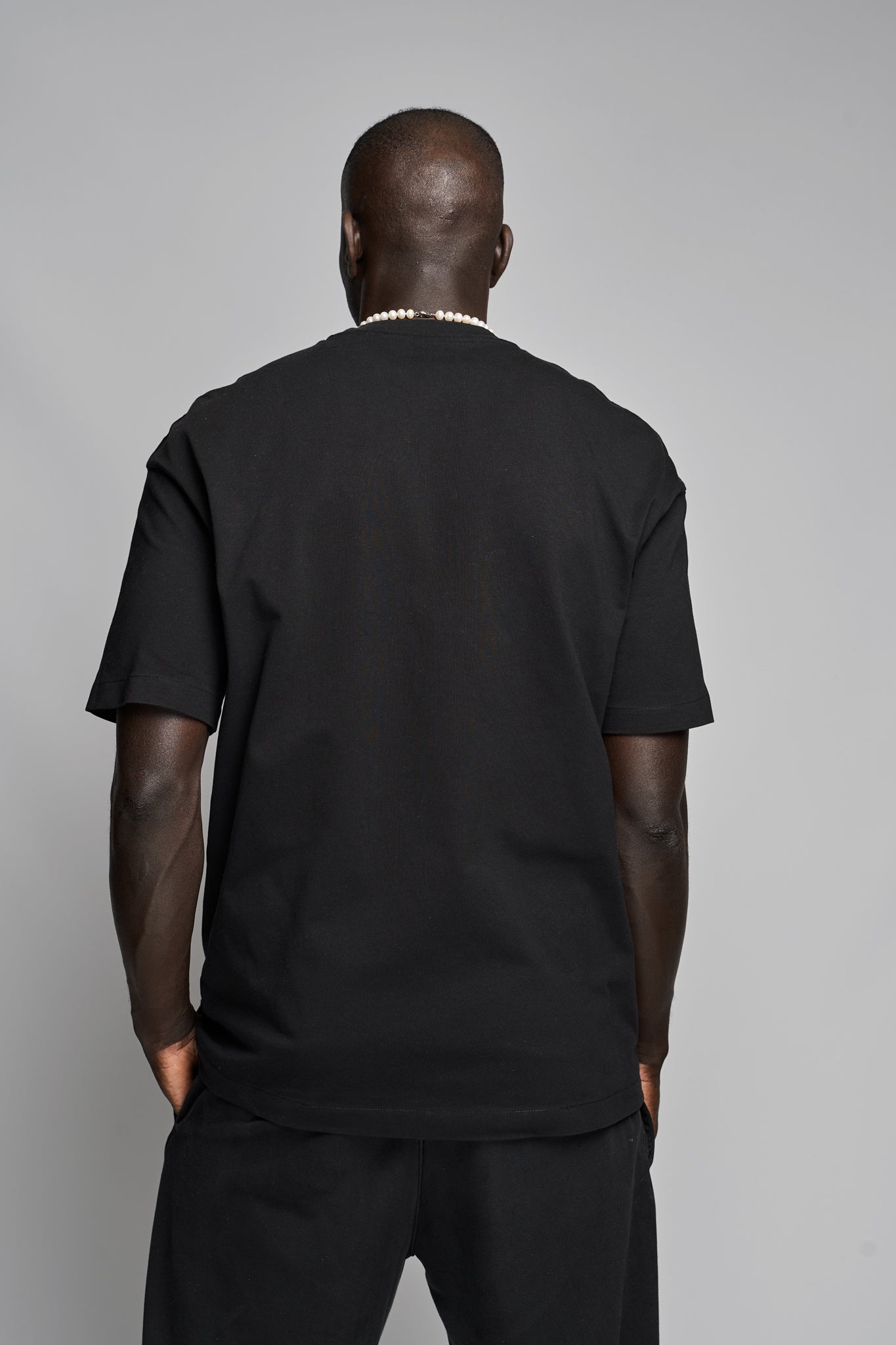 Back view of model wearing Suutoo black organic cotton T-shirt, designed by Kimaa.