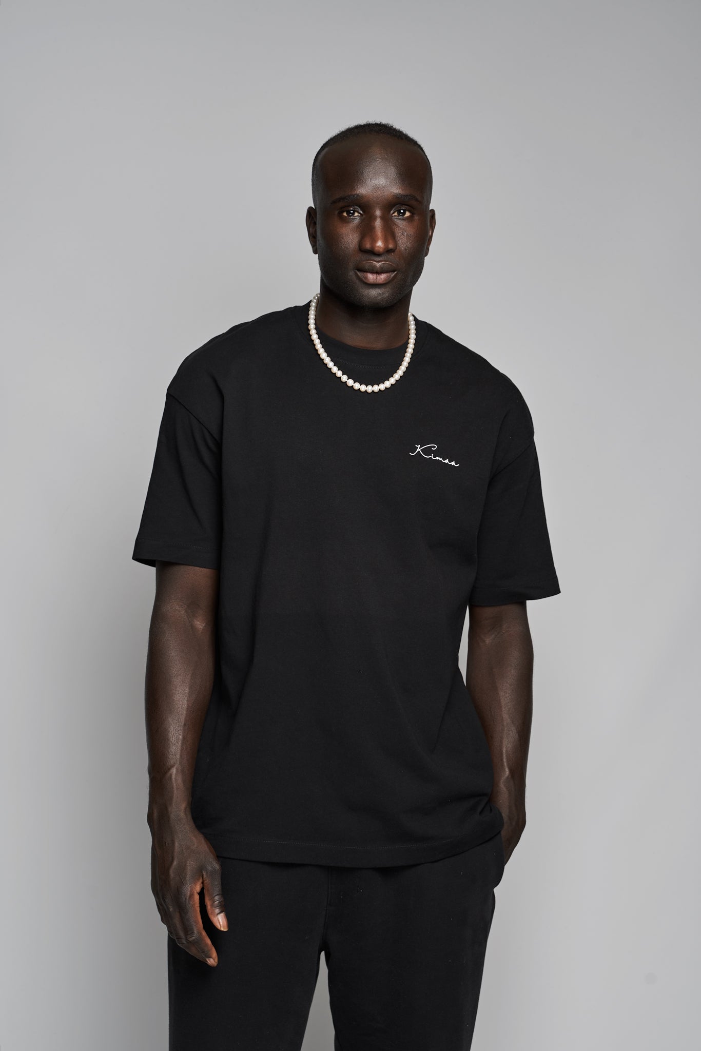 Model wearing Suutoo black organic cotton T-shirt by Kimaa, front view, relaxed fit