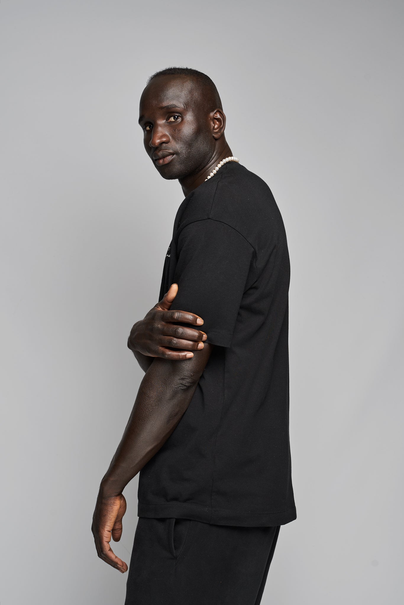 Side profile of Suutoo black organic T-shirt worn by model, showing relaxed silhouette and dropped shoulders