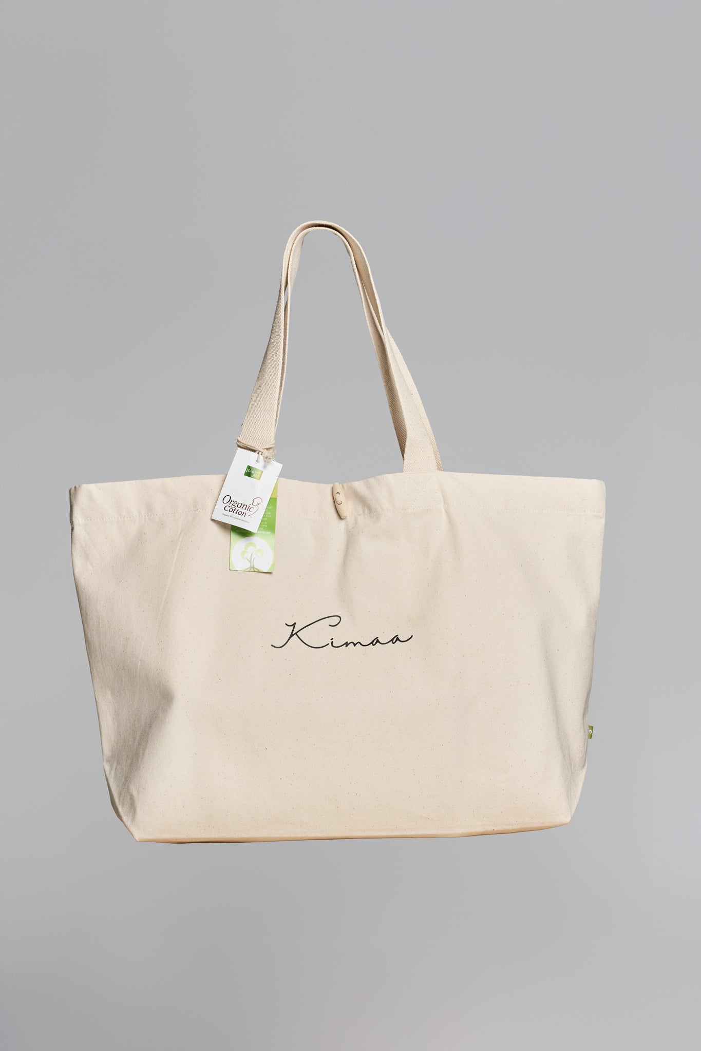 Full front view of Taamoo beige organic cotton tote bag with Kimaa logo and wooden toggle closure.