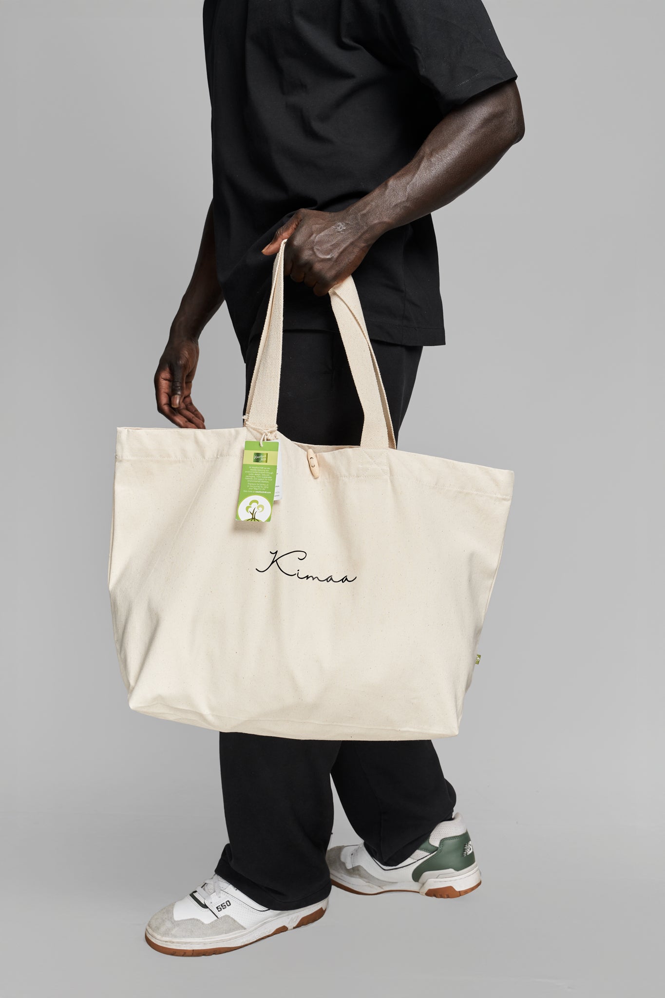 Person carrying beige organic cotton tote bag on their side, showcasing Kimaa’s Afro-Nordic streetwear style.